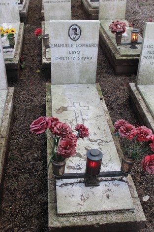 Tombe perpetue con fiori e candele in memoria dei caduti per la Libertà. Atmosfera di rispetto e commemorazione.
