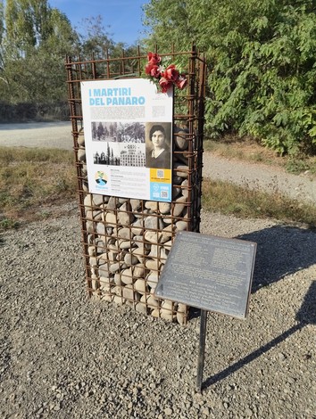 Monumento ai Martiri del Panaro, una struttura commemorativa con immagini e fiori adornanti, immersa nella natura.