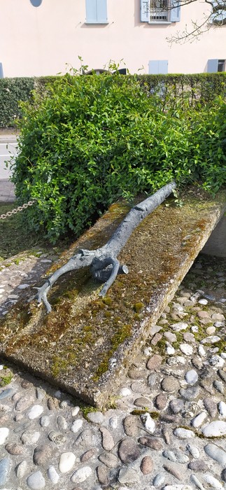 Stele commemorativa con un ramo inciso, immersa nel verde, in un contesto tranquillo di Le Budrie.