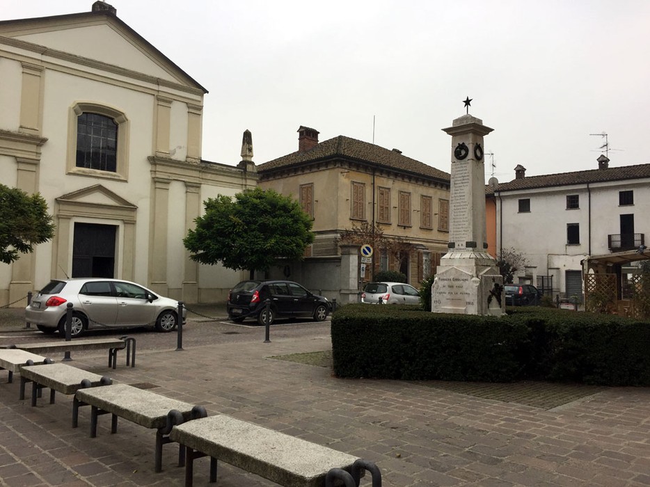 Monumento ai caduti di Ferrera Erbognone, collocato in piazza, circondato da edifici storici e vegetazione.