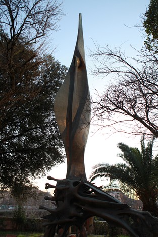 Monumento a Matteotti, scultura stilizzata con forme affusolate, circondata da vegetazione.