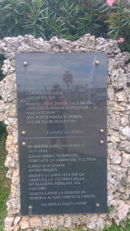 Lapide commemorativa dedicata a Dobrić, Sgagliardi e Boljun, situata in un contesto naturale.
