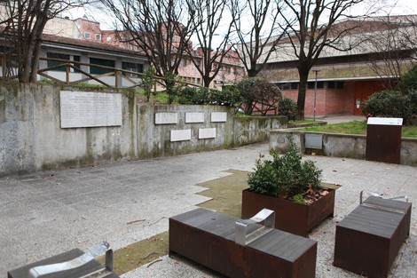 Spazio commemorativo con lapidi dedicate ai figli della stagione partigiana, circondato da vegetazione.