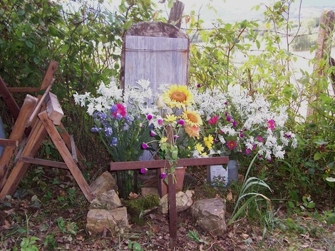 Monumento ai caduti di Terranieri, decorato con fiori e circondato da natura.