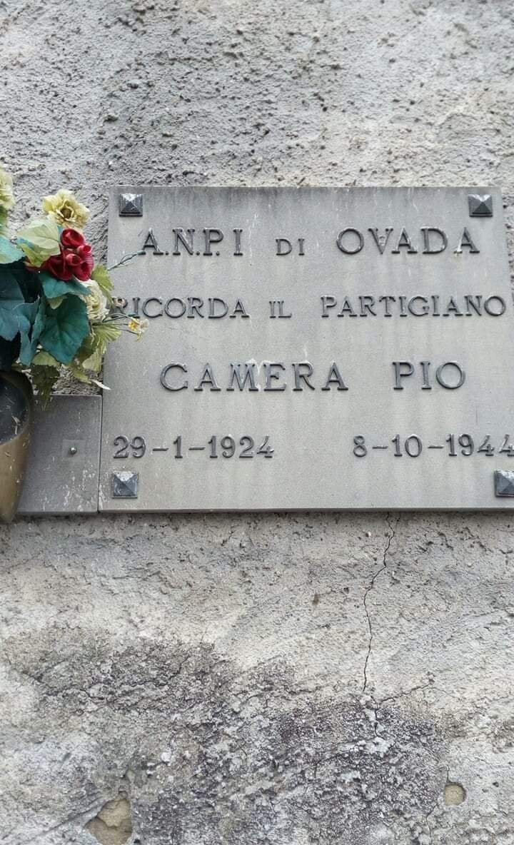 Lapide commemorativa del partigiano Pio Camera ad Ovada, con fiori in omaggio.