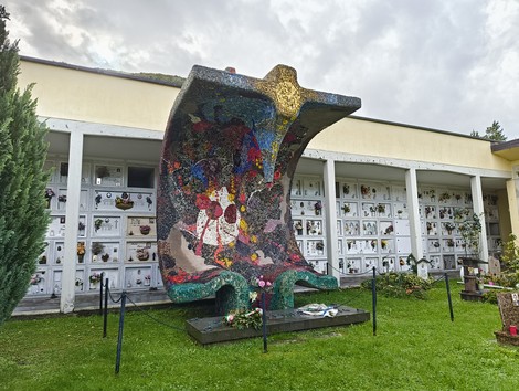 Monumento ai martiri della Creda, una scultura commemorativa immersa nel verde accanto a un cimitero.