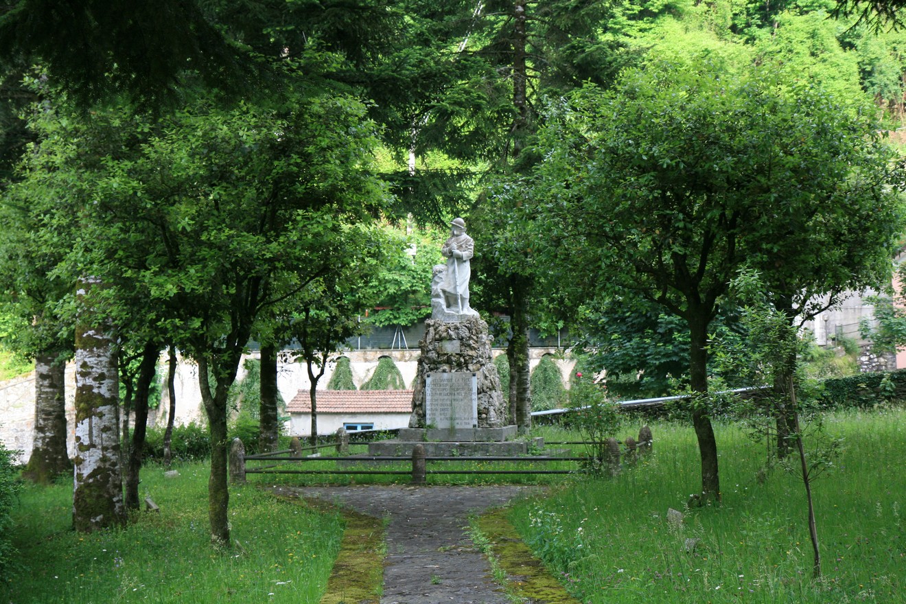 Monumento ai caduti di Mulina, immerso nel verde, circondato da alberi e un sentiero accogliente.