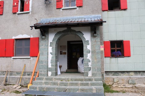Lapide commemorativa all'ingresso del Rifugio Laghi Gemelli, con architettura e dettagli caratteristici montani.