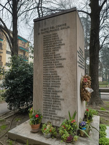 Monumento ai partigiani a San Ruffillo, con nomi incisi e adornato di fiori e una corona commemorativa.