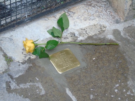 Pietra d'inciampo con una rosa gialla posata accanto, in memoria di Franco e Foà.