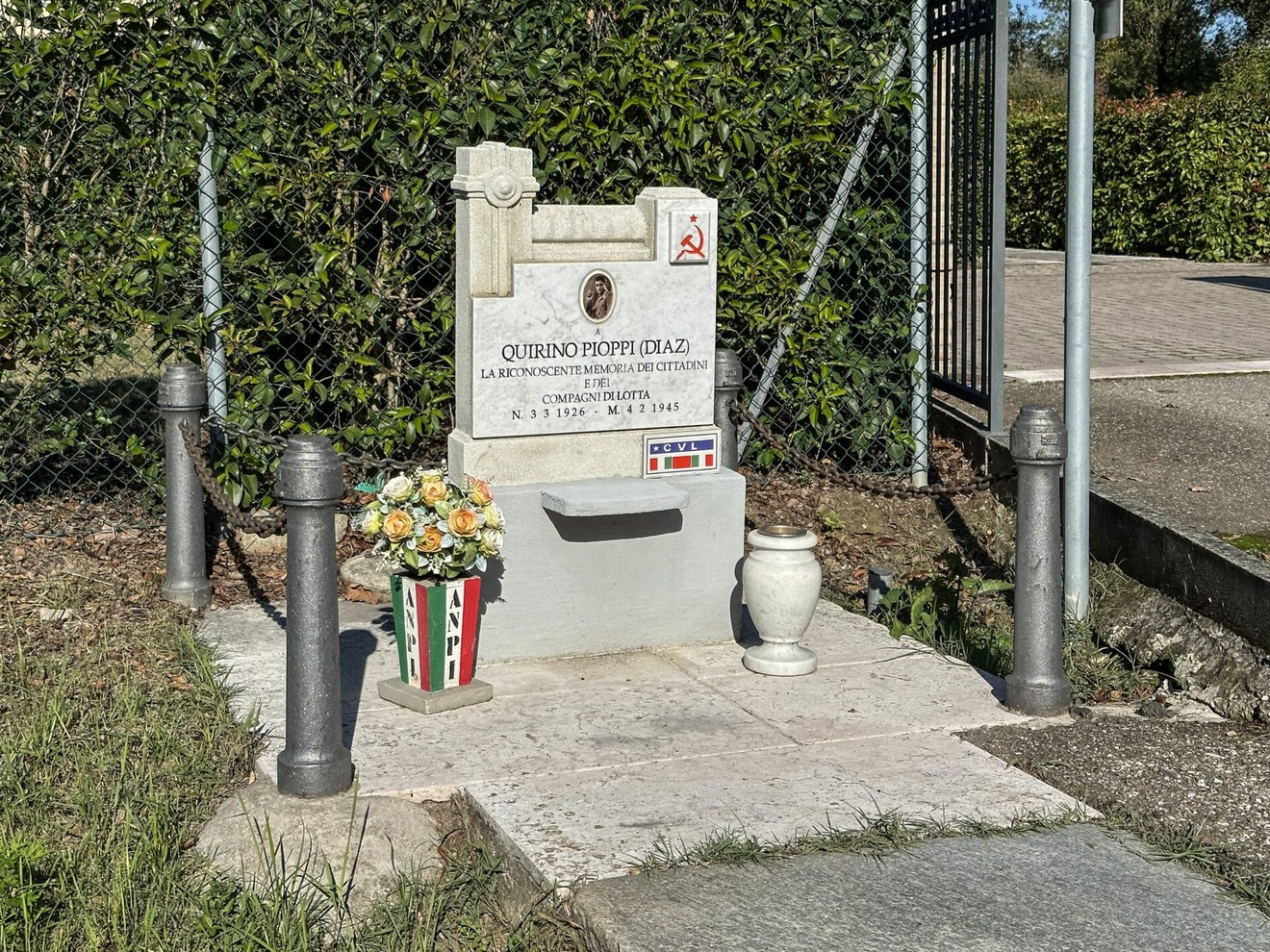 Monumento a Pioppi, dedicato a Quirino Pioppi, con fiori e decorazioni tricolori in onore della sua memoria.