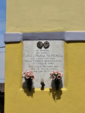 Lapide commemorativa ai coniugi Semenza, con decorazioni floreali su sfondo giallo.