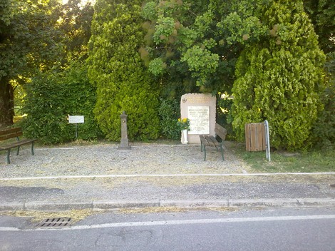 Monumento commemorativo ai Rossi e Bigliardi, circondato da piante e panchine in un'area verde.