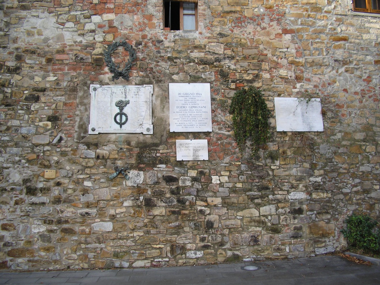 Muro commemorativo ai caduti di San Donato, con lapidi e simboli in memoria dei caduti in guerra.