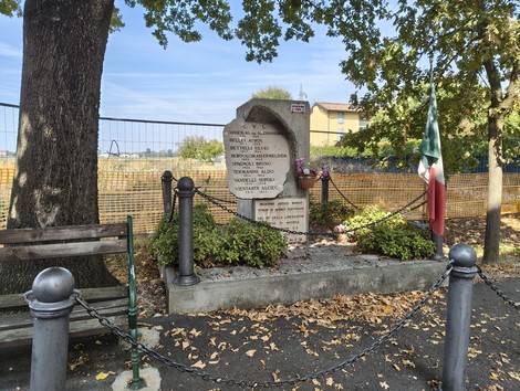 Monumento commemorativo ai caduti per la libertà di Paganine, circondato da piante e decorazioni patriottiche.