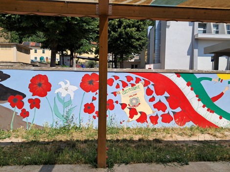 Murale commemorativo con fiori rossi e simboli, dedicato all'80° anniversario della Liberazione di San Piero.