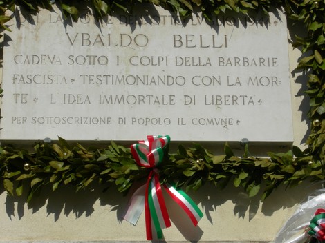 Lapide commemorativa di Vivaldo Belli, dedicata alla memoria e libertà, ornata con un festone di alloro.