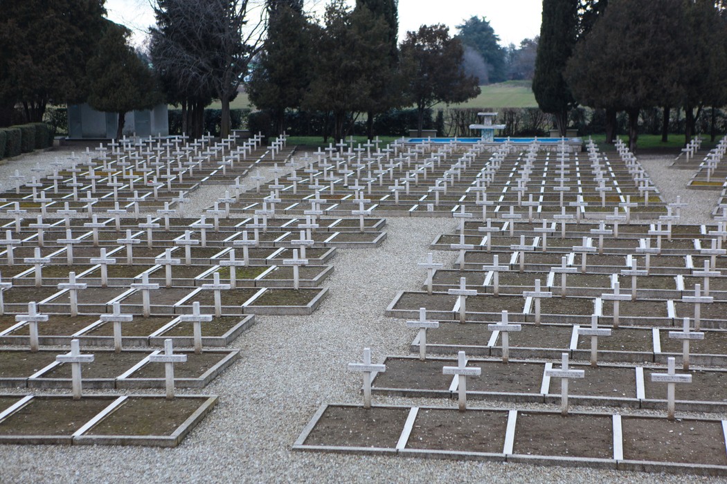 Cimitero di guerra polacco con molte croci bianche disposte ordinatamente su un terreno ghiaioso.