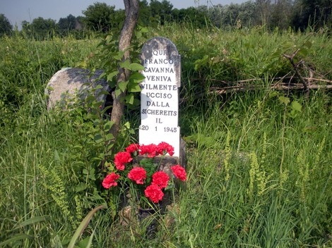 Cippo commemorativo a Cavanna, dedicato a Franco, vittima della guerra, circondato da erba e fiori.