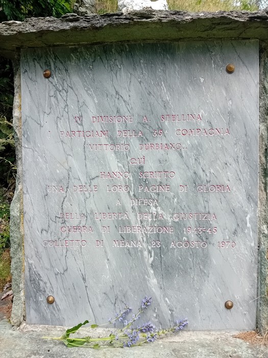 Monumento commemorativo ai partigiani della Divisione Stellina, con incisioni commemorative e decorazioni floreali.