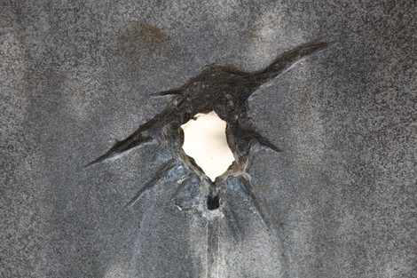 Dettaglio di un monumento con un foro, simbolo di memoria e delle cicatrici della guerra.