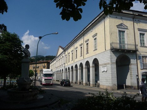 Lapide commemorativa situata a Lovere, circondata da un contesto urbano e vegetazione.