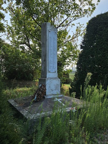 Monumento ai Martiri di Sabbiuno, con un albero sullo sfondo e vegetazione circostante.