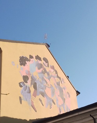 Murale colorato che celebra la memoria dei martiri di Gorla, raffigurante figure in movimento su uno sfondo azzurro.