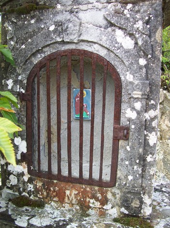 Lapide della Croce del Biserno, monumento di pietra con una nicchia decorativa, immerso nella natura.