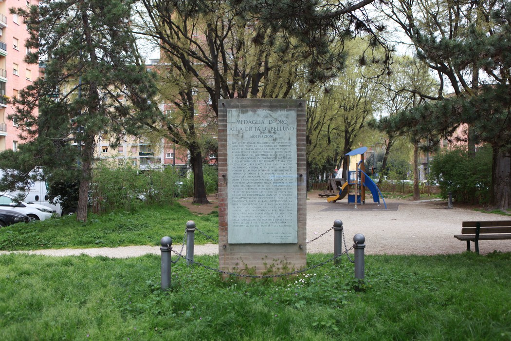 Monumento ai partigiani emiliani e romagnoli, circondato da verde e giochi per bambini in un parco.