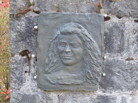 Rilievo commemorativo in bronzo dedicato a Guidetti, incastonato in un muro di pietra.