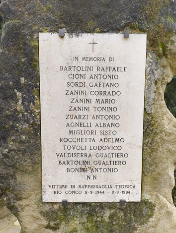 Monumento commemorativo in memoria delle vittime di Rio Conco, con targa affissa su una roccia.