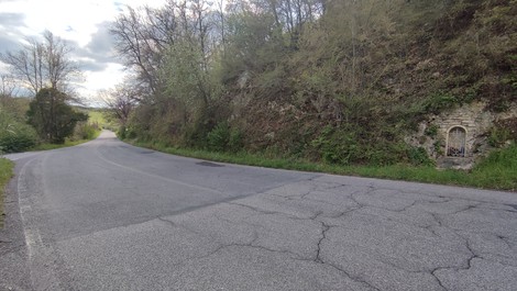 Edicola per Panichi situata lungo una strada circondata da vegetazione e colline.