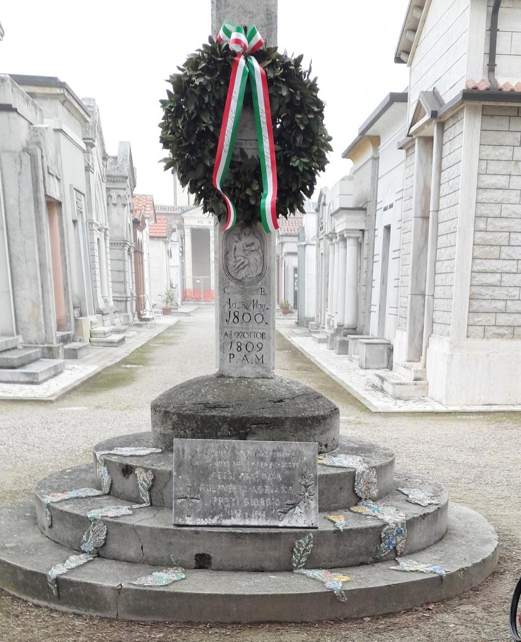 Lapide commemorativa in ricordo dei caduti nei lager, decorata con una corona e simboli italiani.