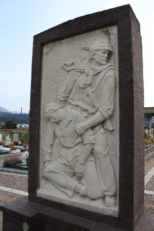 Monumento ai Caduti partigiani con scultura raffigurante un soldato e un compagno in difficoltà.