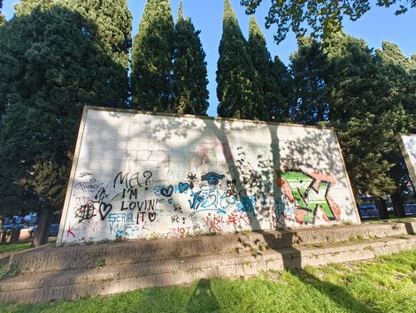 Monumento alla Liberazione e alla Pace, decorato da graffiti, incastonato tra alberi maestosi.