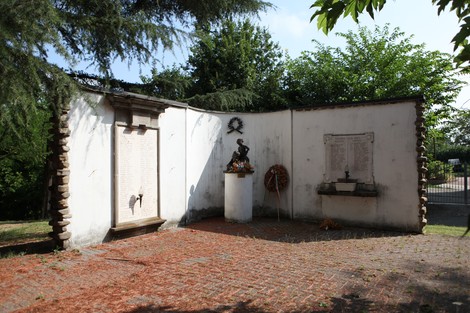 Il Monumento ai Caduti, un memoriale con iscrizioni e una scultura, immerso nel verde.