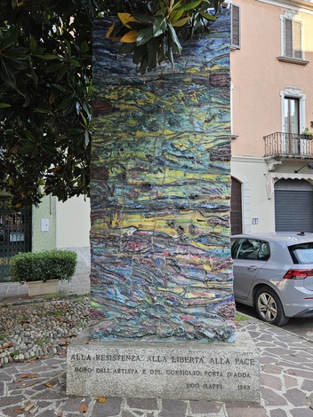Monumento colorato dedicato alla Resistenza, alla Libertà e alla Pace, circondato da un contesto urbano.