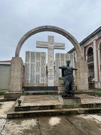 Monumento al "Campo della Gloria", dedicato ai caduti, con statua e lista commemorativa in un contesto sereno.