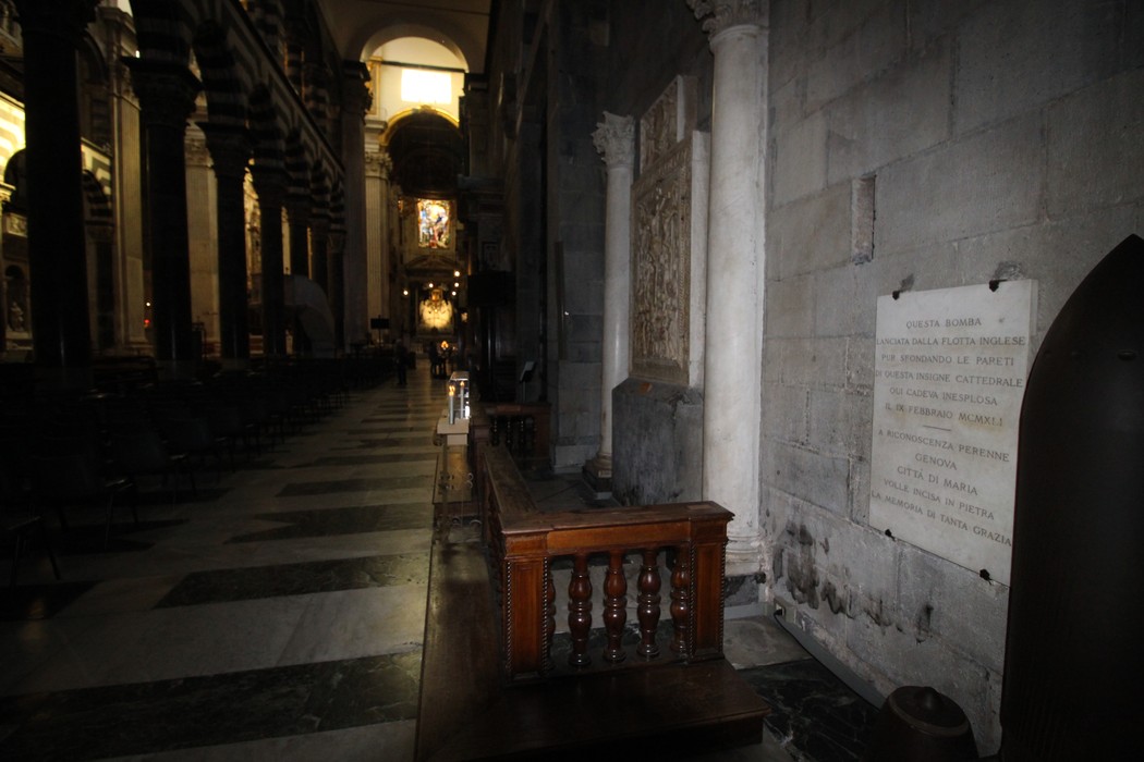 Lapide commemorativa per una bomba inesplosa, situata all'interno di una chiesa con architettura storica.