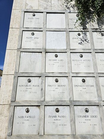 Monumento ai Caduti Partigiani con targhe commemorative e sfondo blu del cielo.