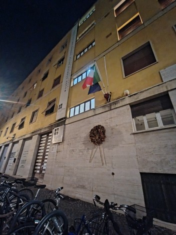 Lapide commemorativa all'esterno del carcere di via Tasso, con bandiere e decorazioni natalizie.