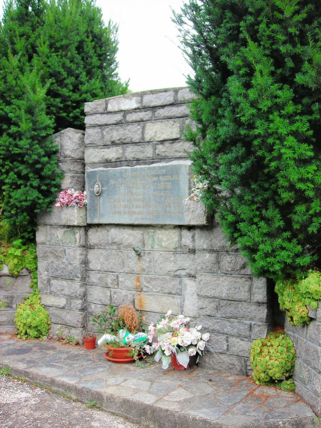 Monumento a Cabrio, commemorativo, con vegetazione e fiori ornamentali ai piedi della struttura.