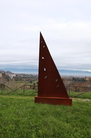 Scultura nel Parco della Rimembranza, circondata da un paesaggio verde e collinare, simbolo di memoria e natura.