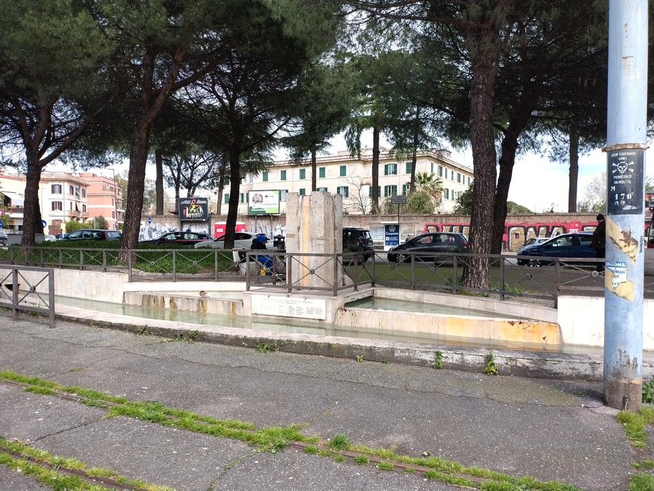 Monumento ai caduti per la libertà di Centocelle, circondato da alberi e strade città.