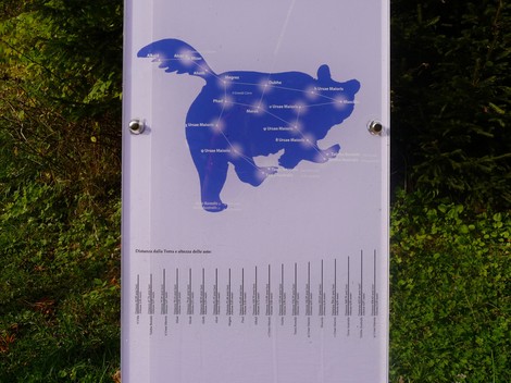 Immagine di un pannello informativo che illustra il "Monumento ai Dodici Caduti" con sfondo naturale.