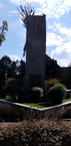 Monumento ai combattenti per la Libertà, con simboli patriottici e vegetazione circostante.