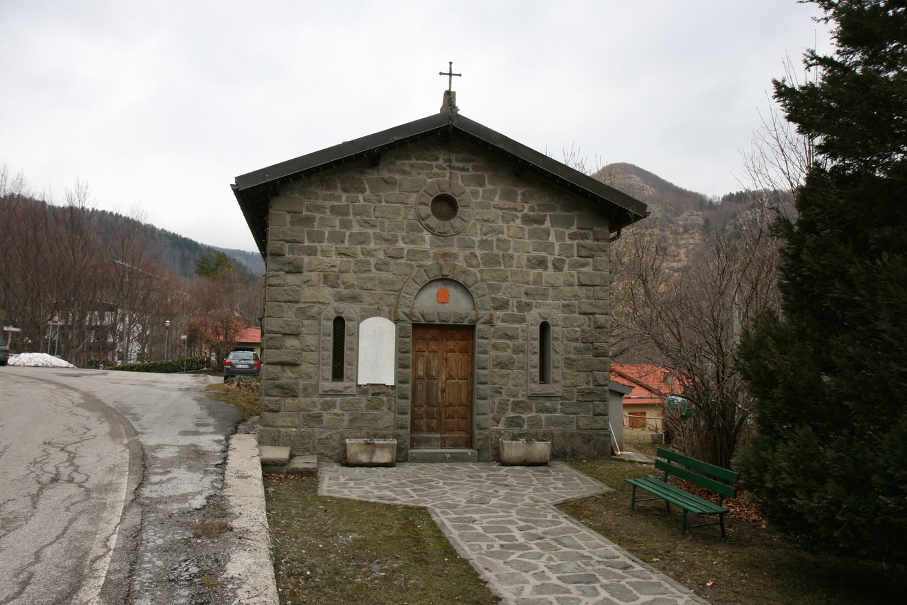 Lapide commemorativa ai caduti, situata a Pian di Novello, di fronte a una piccola chiesa in pietra.