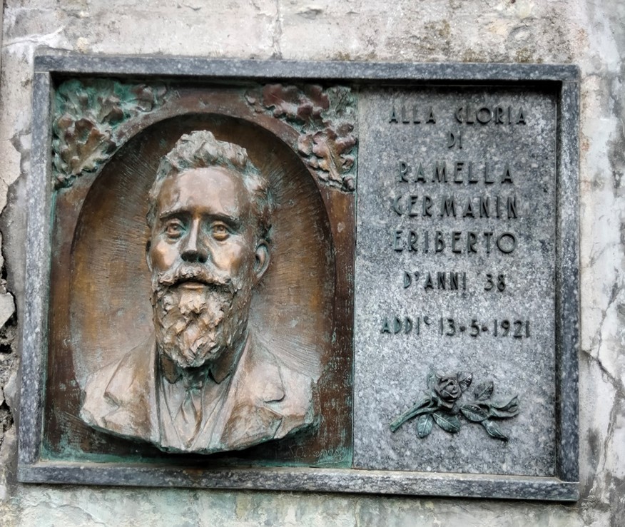 Lapide commemorativa di Ramella Germain, eroe caduto, con riflesso della sua immagine e data di memoria.