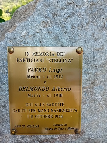 Cippo commemorativo dedicato ai partigiani Favro e Belmondo, situato in un contesto naturale.